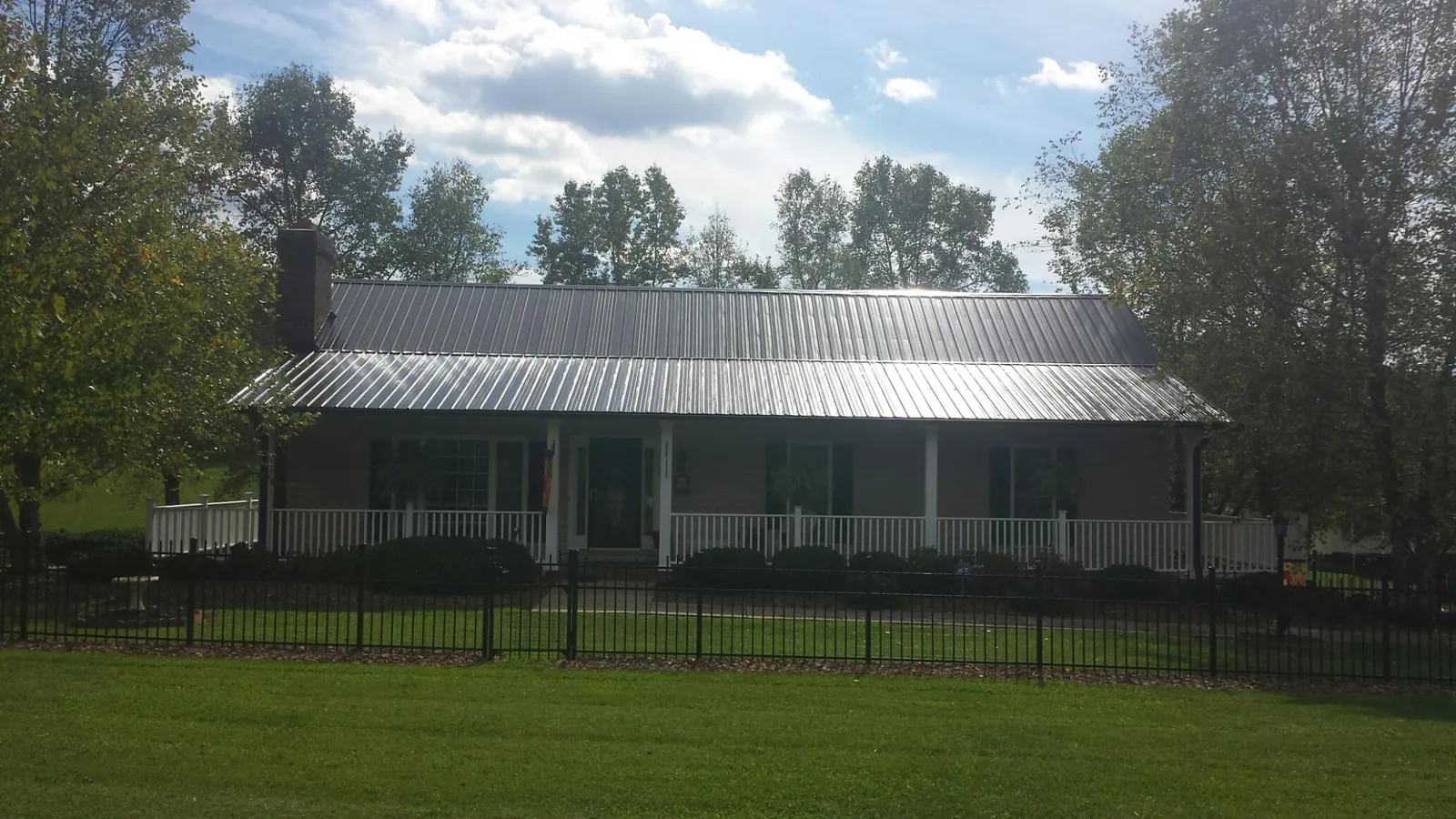 Gray metal roof on a brick ranch with a full width front porch — Gutter Guard Installation work by our crew in Mc Clure